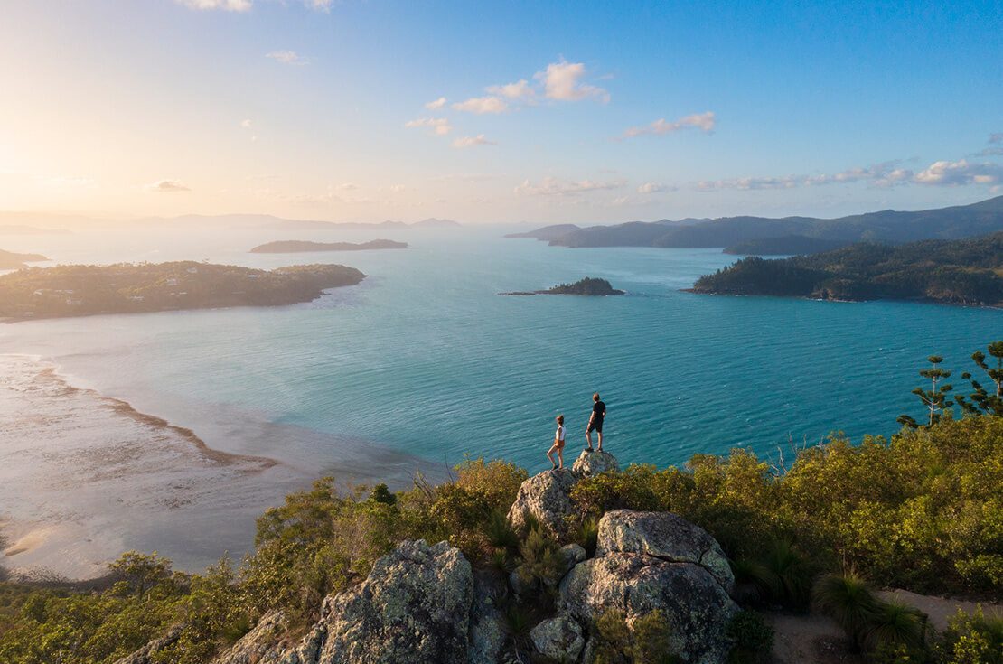 Couple enjoying the view on top mountain overlooking Whitsundays ocean